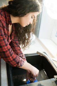 Woman cleaning a clogged kitchen sink.
