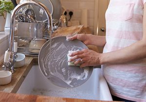 Woman's hands washing a plate at the sink