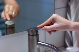 Person turning on the sink faucet 