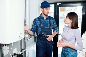 service pro explains advantages of tankless water heater to woman customer