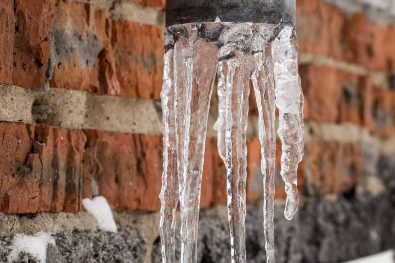 frozen water hanging from pipes outside from poor pipe winterization